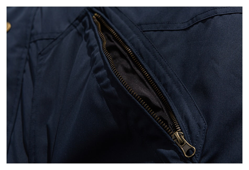 Close-up of a navy jacket pocket with an open brass-colored zipper.