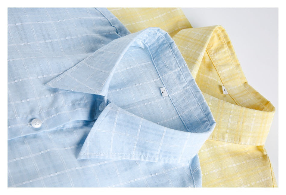 Close-up of overlapping light blue and pale yellow checked shirts, highlighting their collars and buttons.