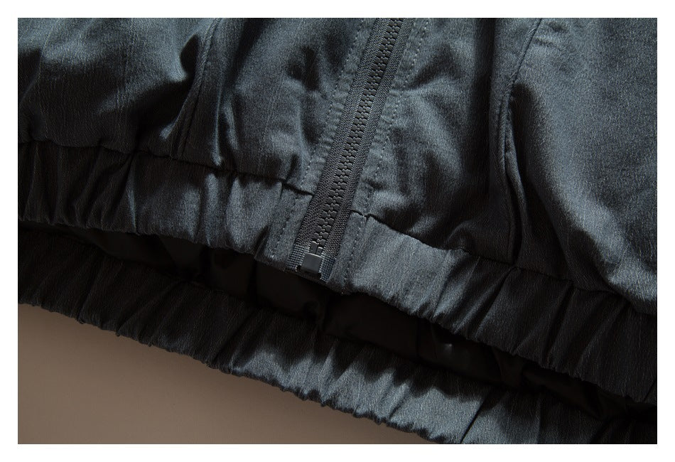 Close-up of a zipper and gathered hem on a dark charcoal jacket.