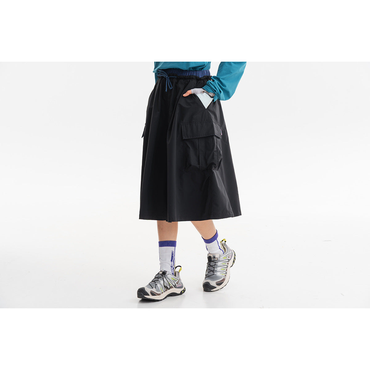 Cropped view of a model wearing a black wide midi cargo skirt with an elastic drawstring waist.