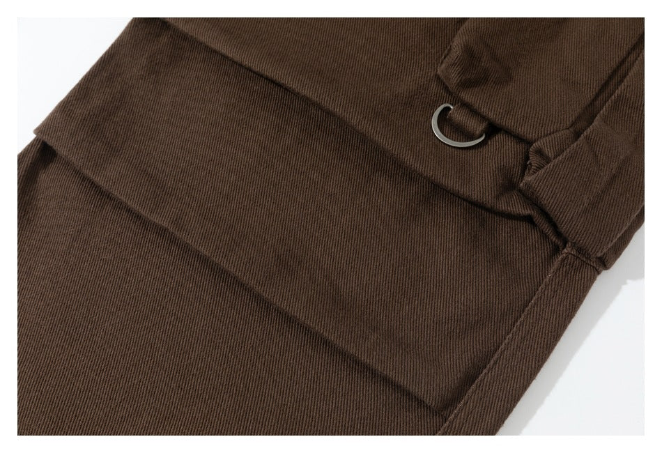 Close-up of a brown cargo trouser leg with a large pocket and metal D-ring.