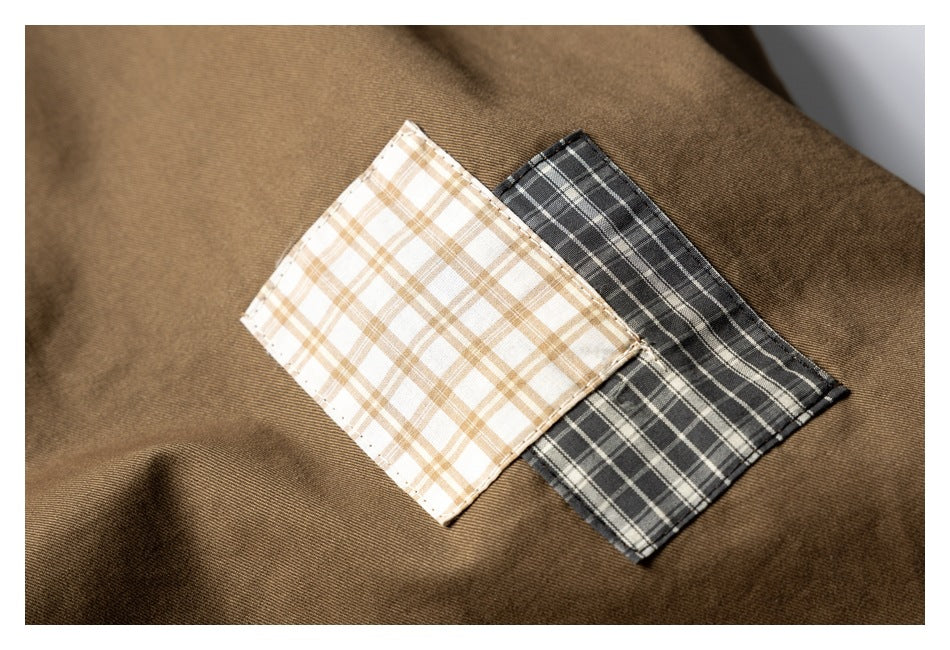 Close-up of brown fabric with two overlapping plaid swatches in cream and tan, and charcoal gray.