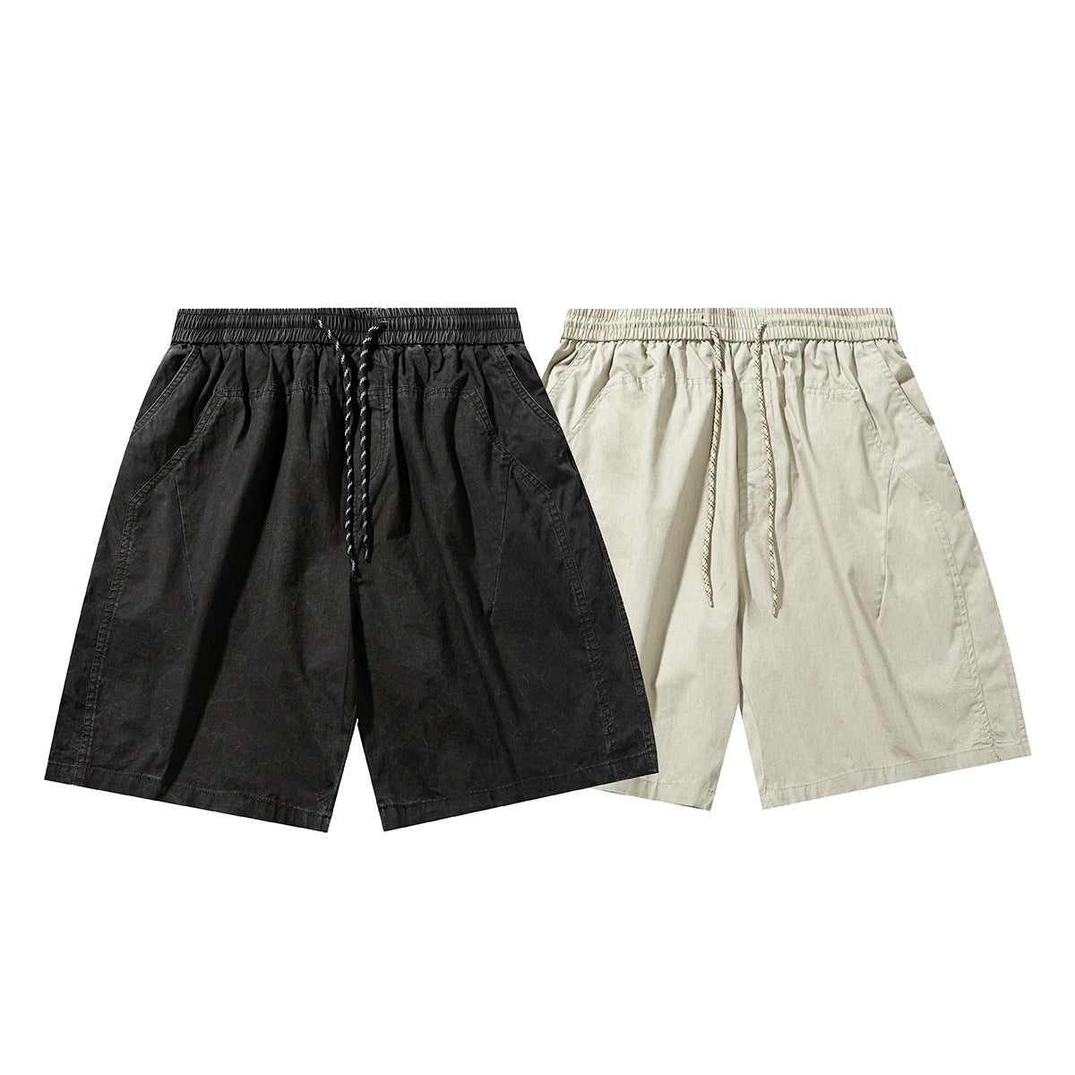 Front views of relaxed shorts in black and light beige, each with an elastic drawstring waist and angled pockets.