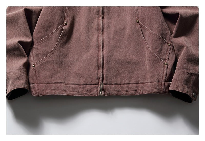 Close-up of the mauve-brown jacket front showing curved pockets, metal rivets, center zipper, and hem.