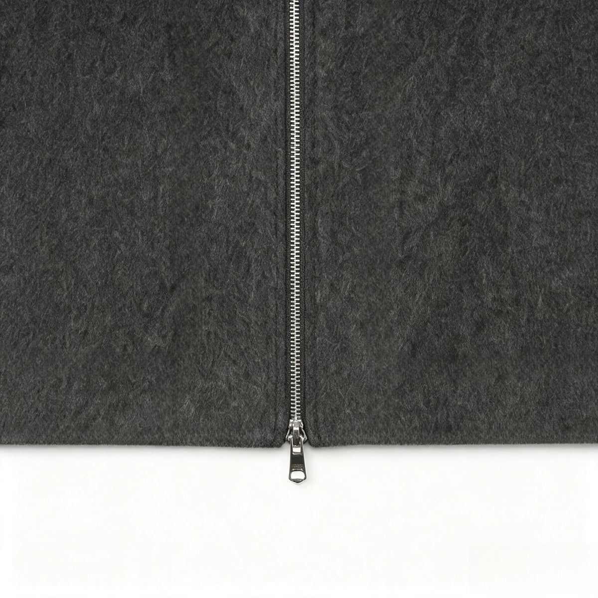 Close-up of the charcoal gray jacket's front with a silver zipper and textured surface.