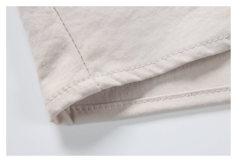 Close-up of a pale beige garment hem showing folded edges and stitching.