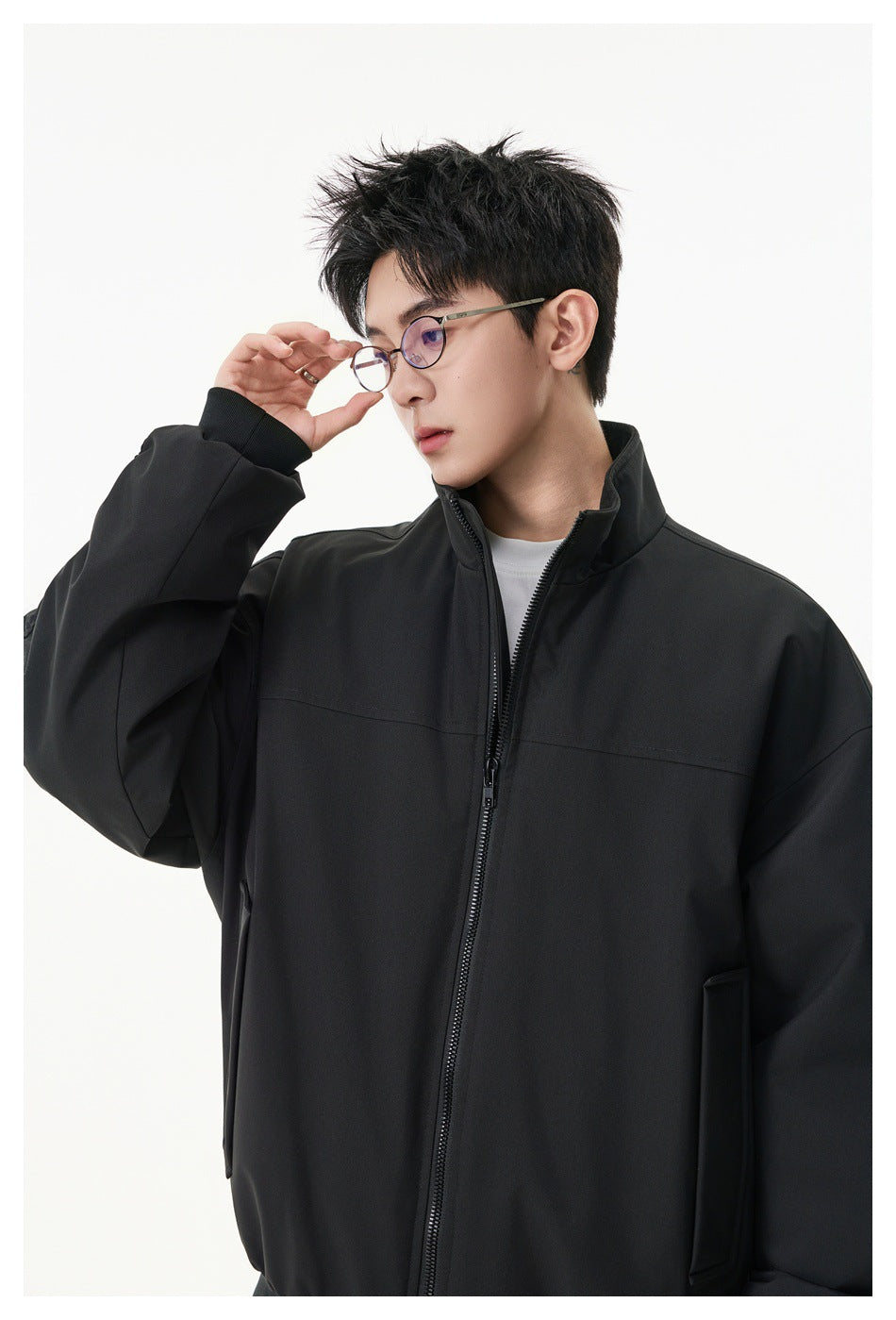 Close view of a model wearing a black zip-up jacket with a stand collar and front pockets.