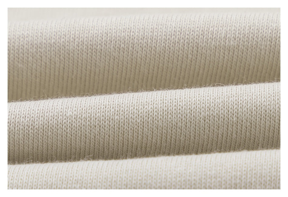 Close-up of pale cream knit fabric showing its fine vertical stitch pattern.
