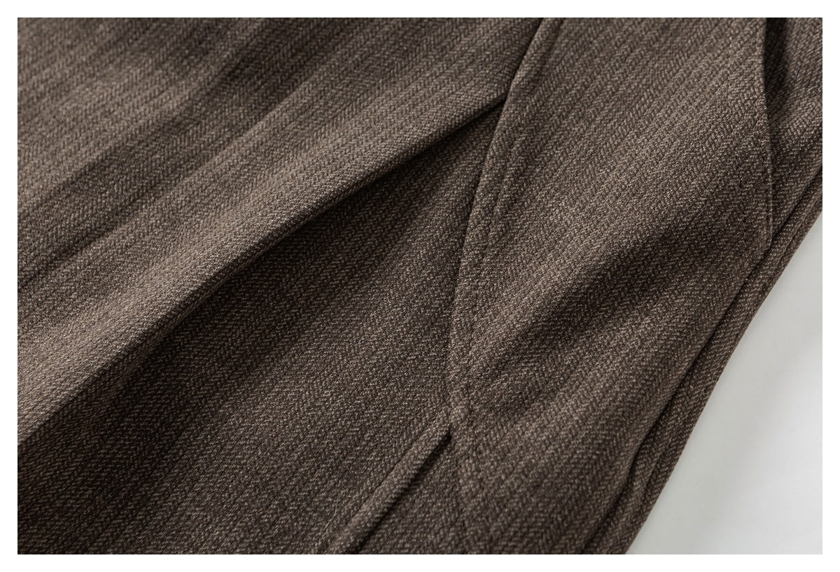 Close-up of the taupe trousers' textured fabric and folded seam details.
