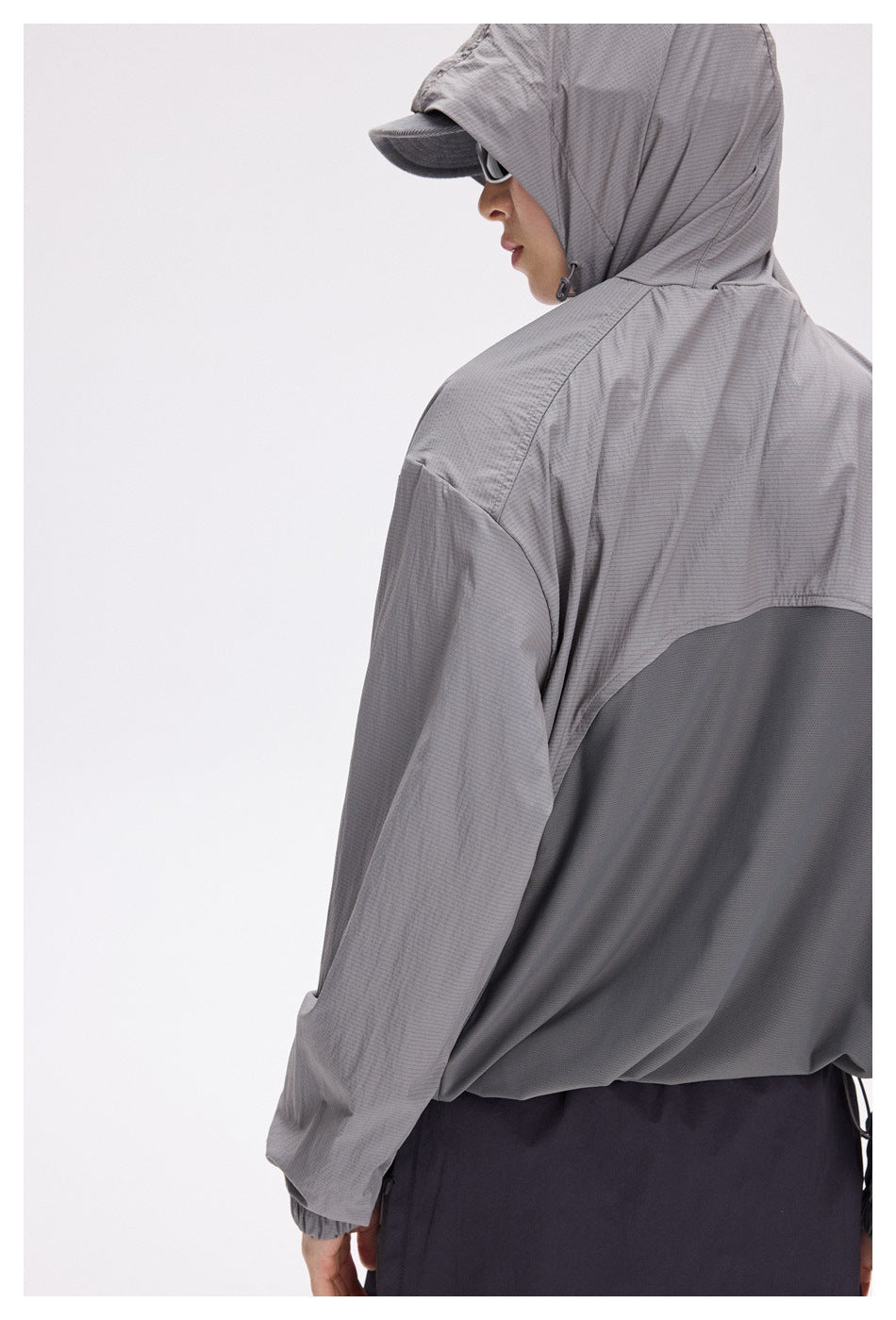 Close rear view of a gray hooded jacket, showing the contrasting dark back panel and gathered cuff.