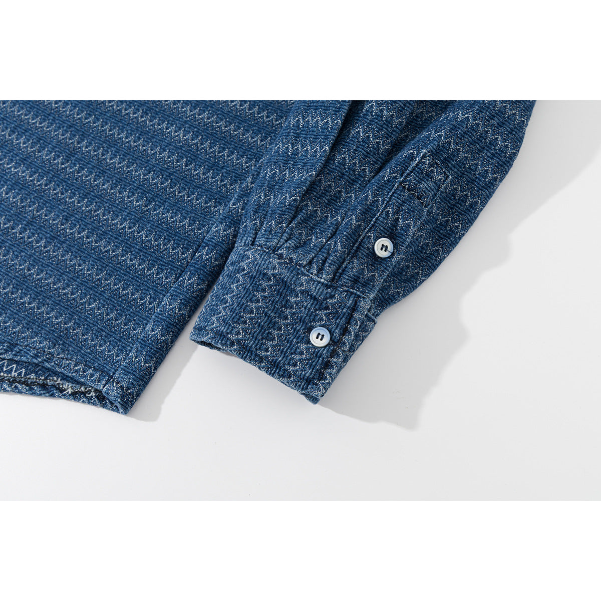 Close-up of a blue patterned shirt sleeve cuff with two white buttons.