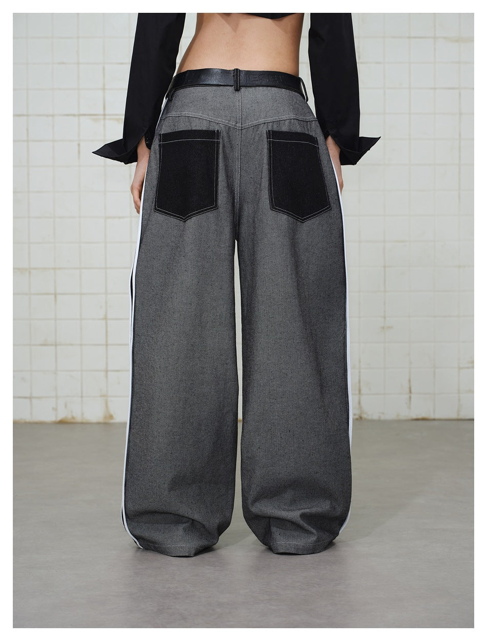 Back view of a model wearing wide gray trousers with black back pockets and narrow white side stripes.