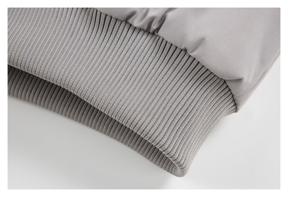Close-up of a light gray jacket’s ribbed knit cuff and smooth sleeve.