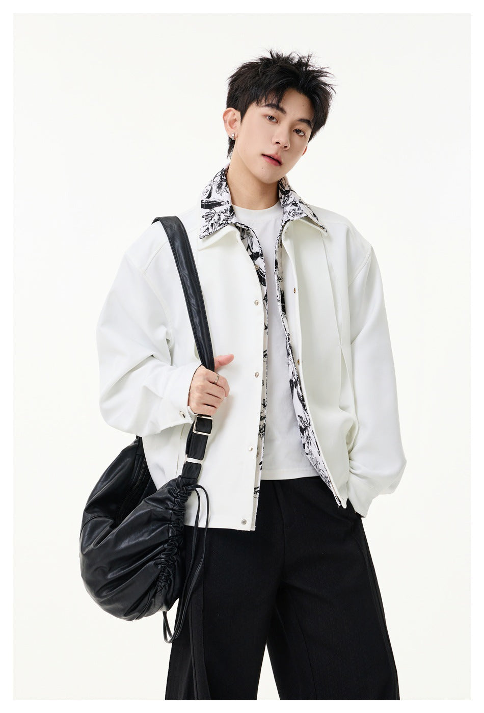 Model wearing the white jacket with printed collar over a white tee and black pants, carrying a black bag