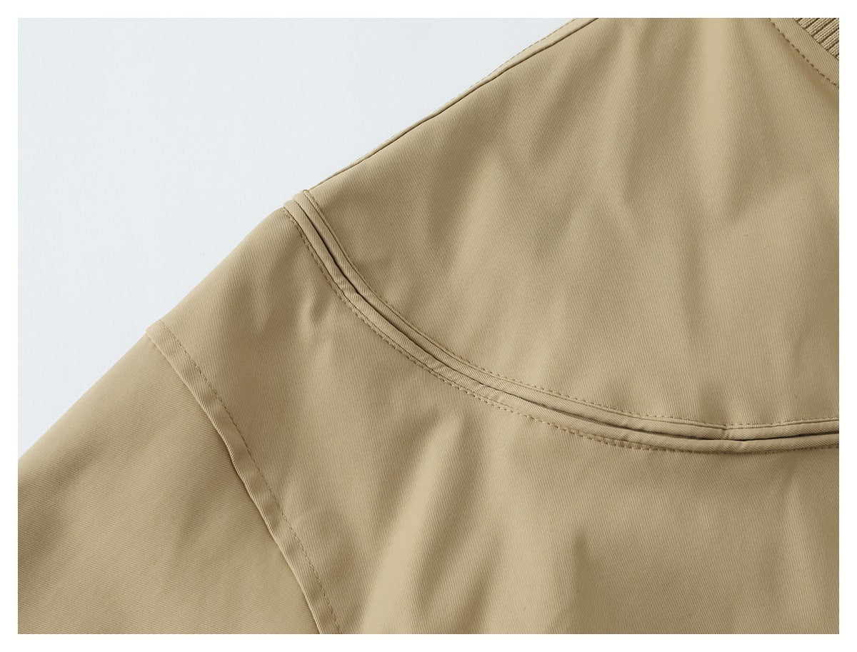 Close-up of the tan jacket's curved shoulder yoke seam and sleeve stitching.