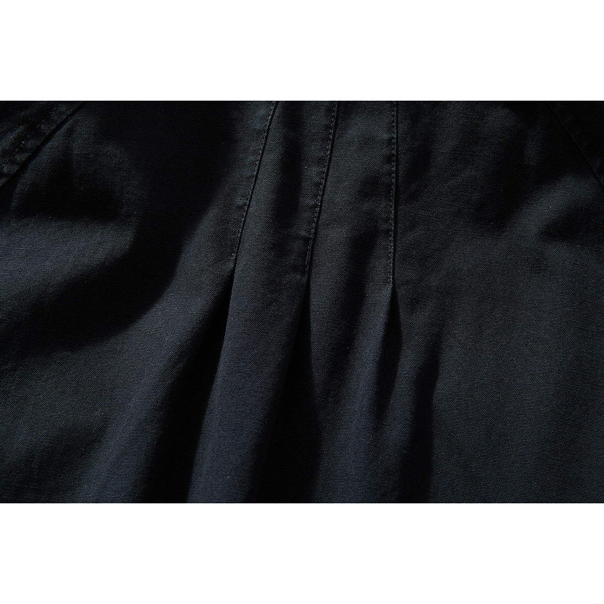 Close-up of black jacket fabric and a central stitched seam.