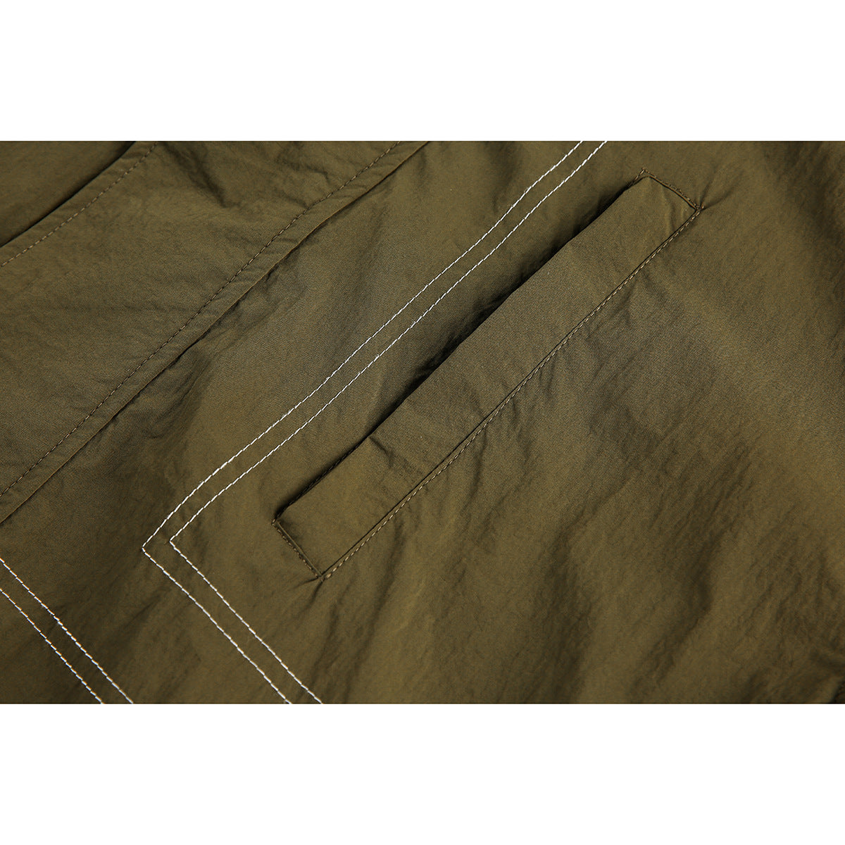 Close-up of an olive jacket pocket flap with parallel contrasting stitch lines.