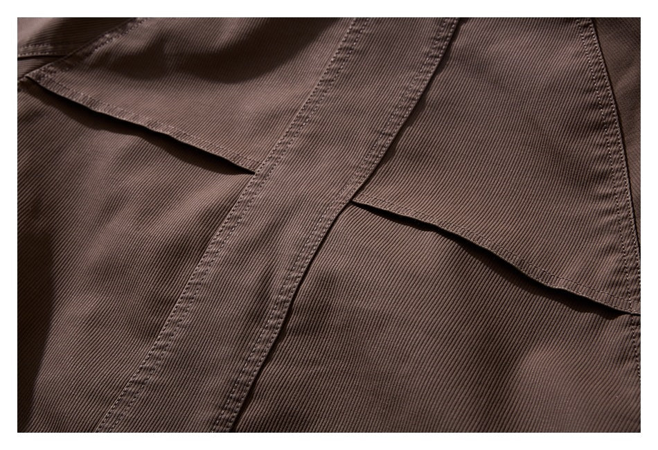 Close-up of a brown jacket flap pocket with ribbed fabric and reinforced stitching.