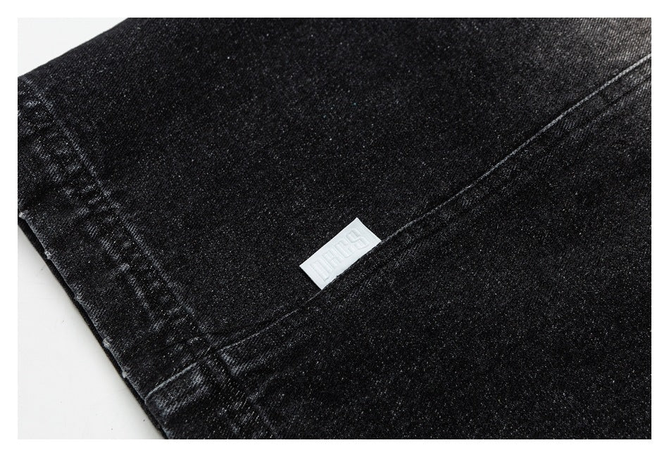 Close-up of black pants with stitched seams and a small white fabric label.