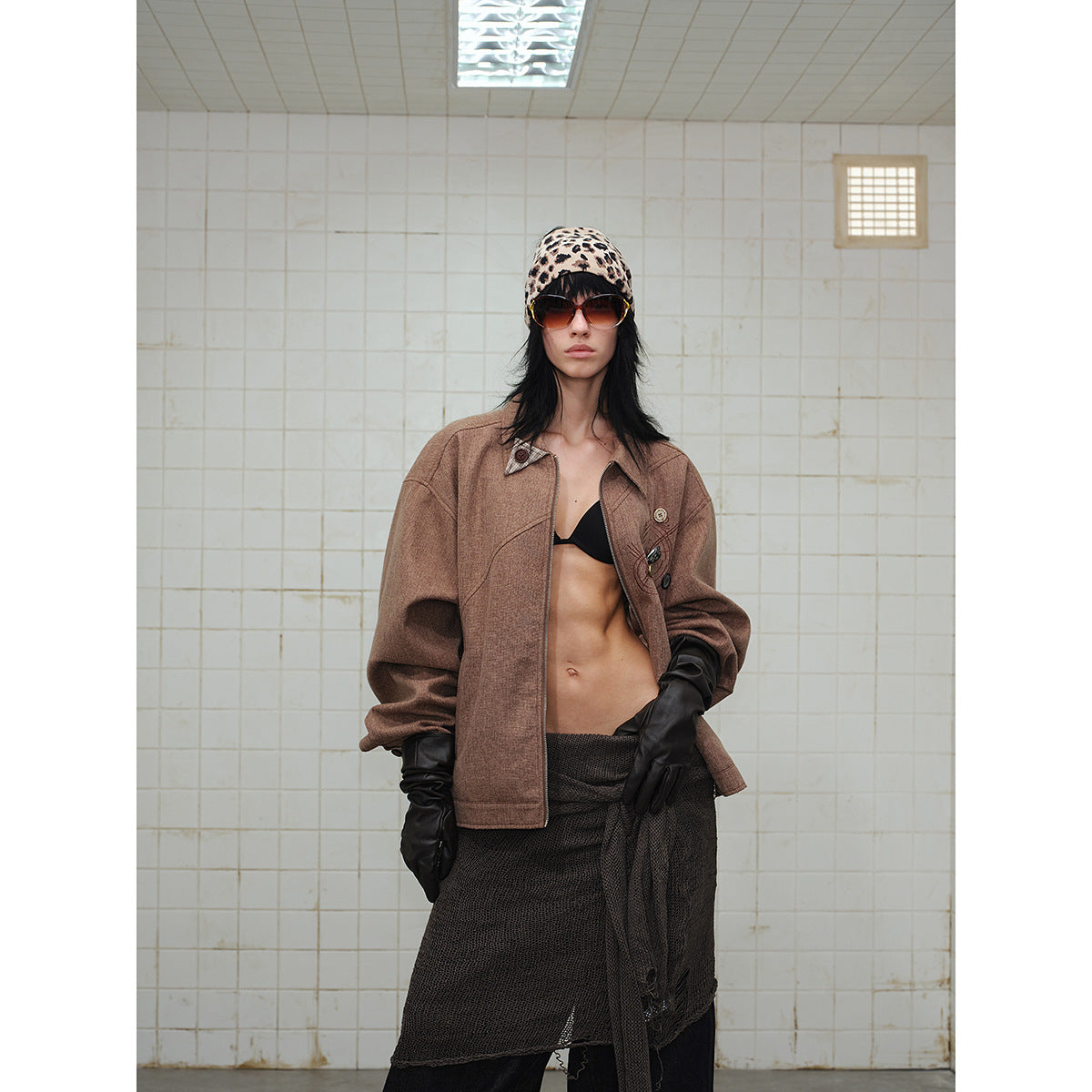 Closer front view of a model in a brown zip-front jacket with decorative chest stitching and buttons.