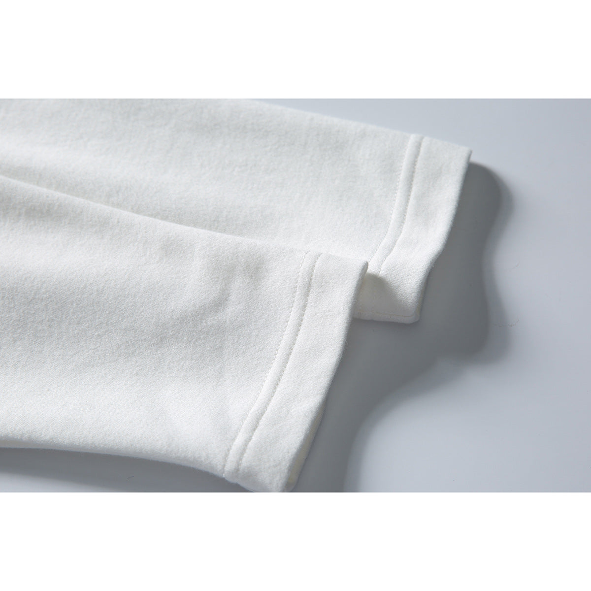 Close-up of a white sweatshirt sleeve and stitched cuff edge.