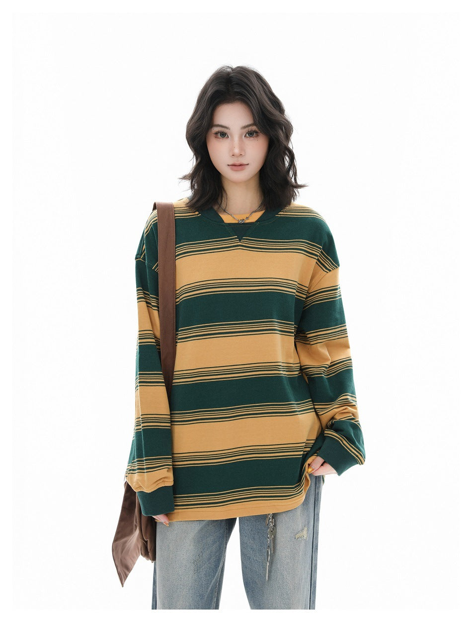 Model wearing an oversized yellow and green striped sweatshirt with light jeans and a brown shoulder bag