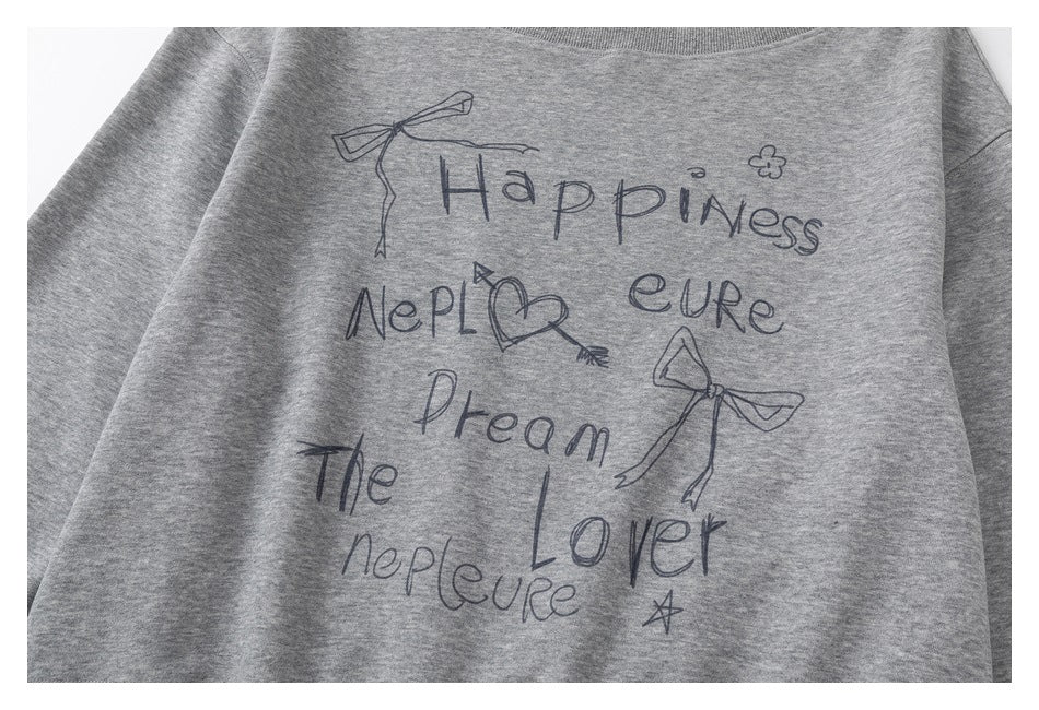 Close-up of a heather-gray sweatshirt front with a dark hand-drawn-style English word and bow, heart, and star graphics.