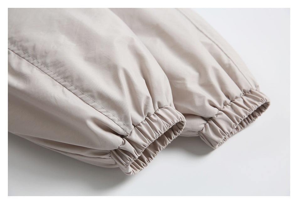 Close-up of the light beige jacket's gathered elastic cuffs and stitched sleeve seams.