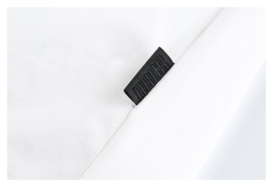 Close-up of a small black woven tag sewn into the white T-shirt.