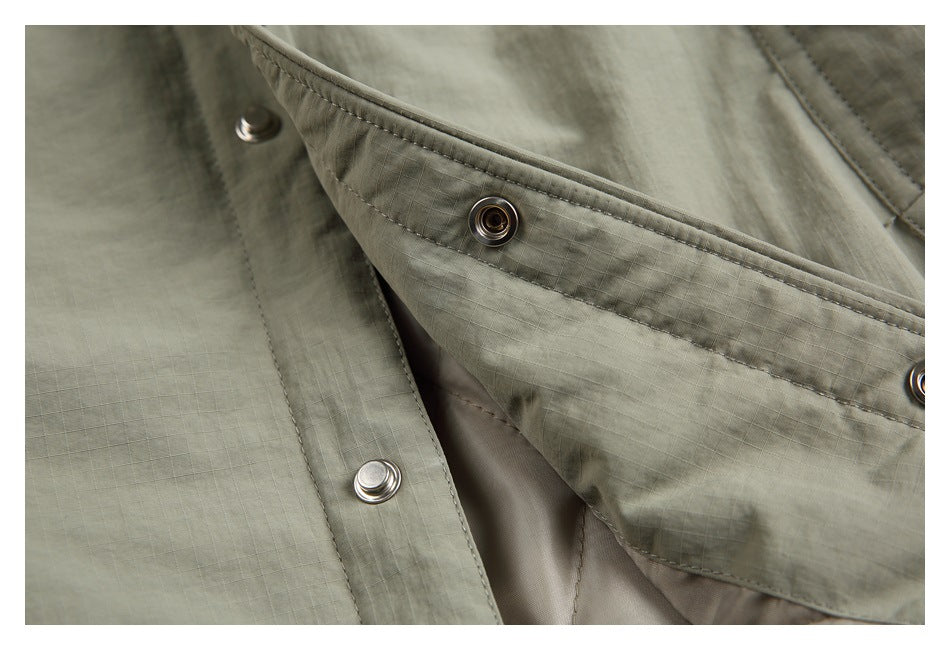 Close-up of the gray-green jacket's stitched snap-button placket and fabric texture.