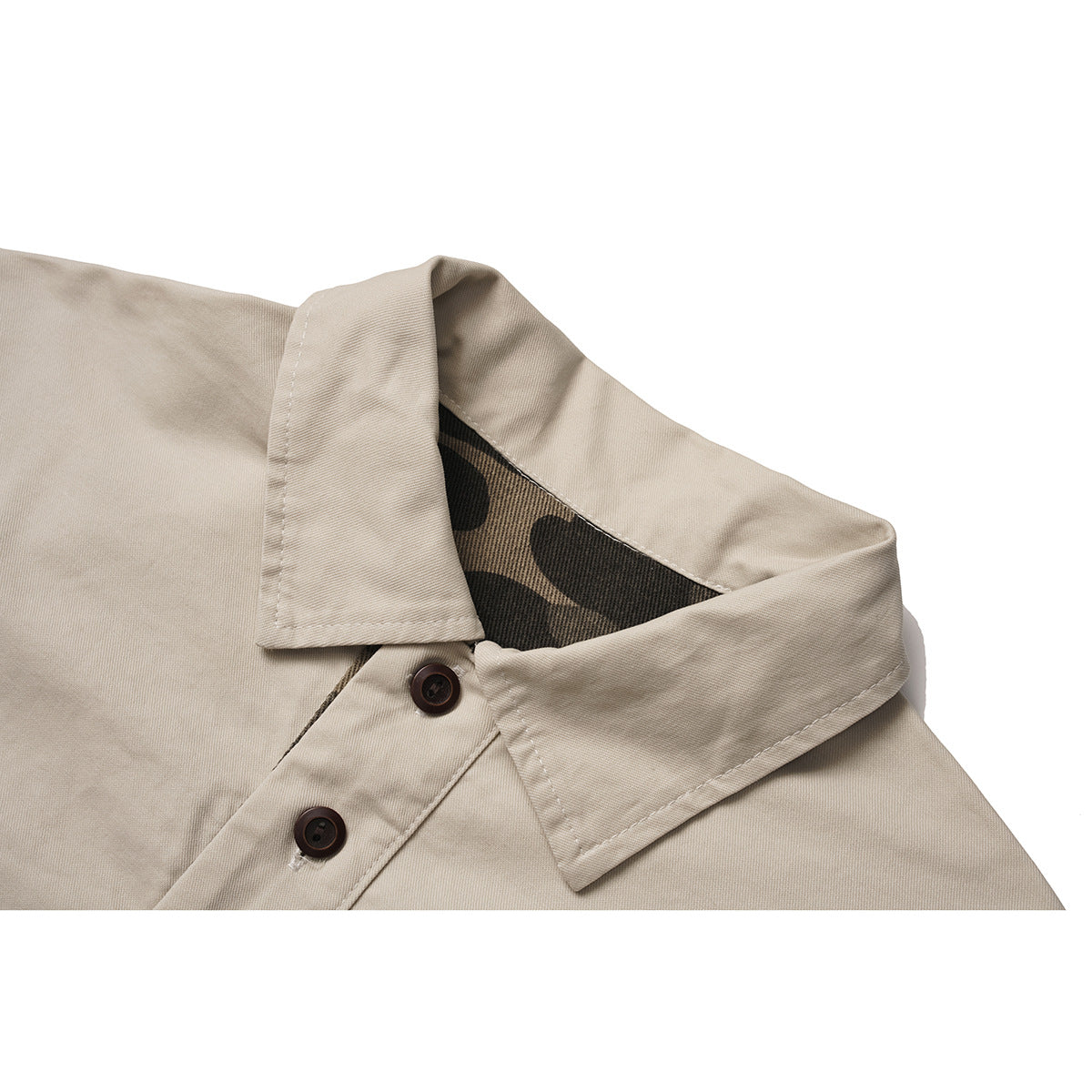 Close-up of a beige collared shirt showing dark buttons and camouflage-patterned inner collar lining.