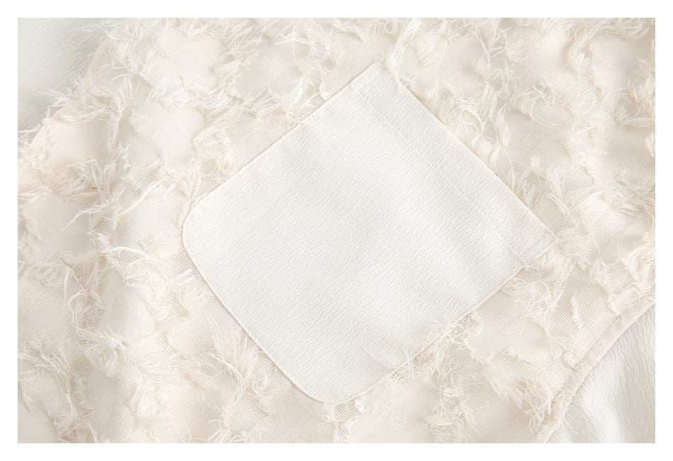 Close-up of a white patch pocket on a shirt with frayed floral appliqué.