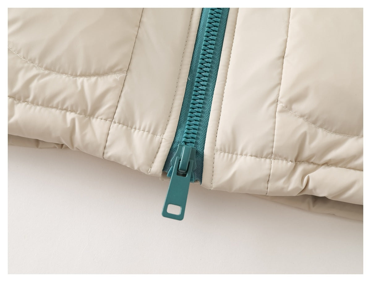 Close-up of the teal zipper and long pull at the hem of a cream quilted jacket.