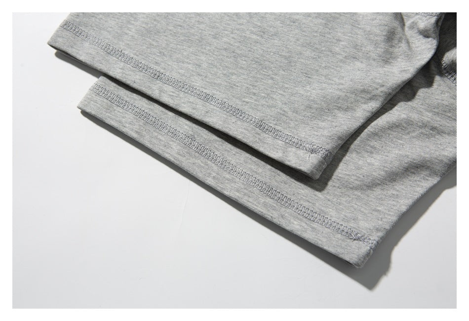 Close-up of the gray T-shirt's sleeve and body hems with overlock stitching.