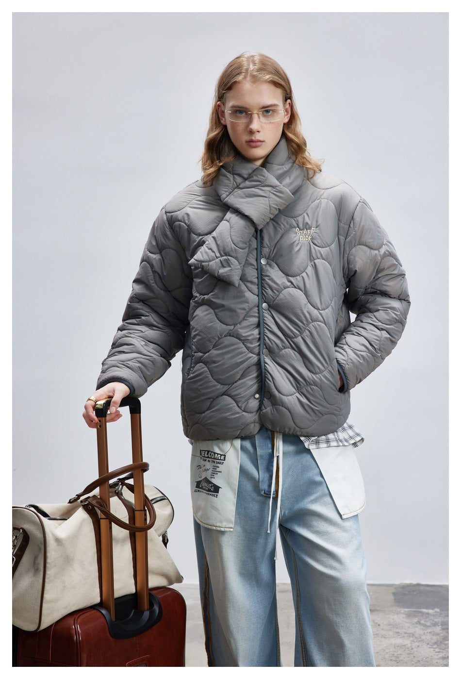 Front view of a model wearing a gray wave-quilted jacket with snap closures and a matching scarf.