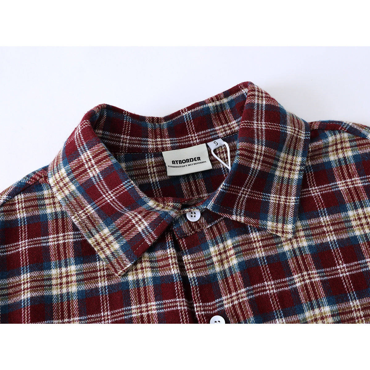 Close-up of a burgundy, navy, cream and tan plaid shirt collar, buttons and sewn-in neck label.