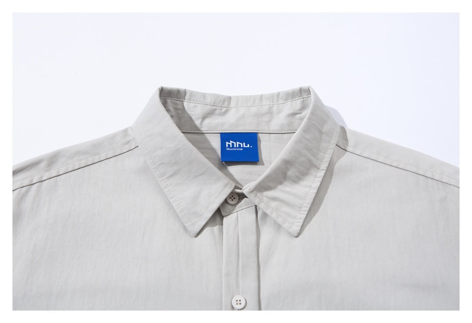 Close-up of the light gray shirt's pointed collar, top buttons, and blue neck label.