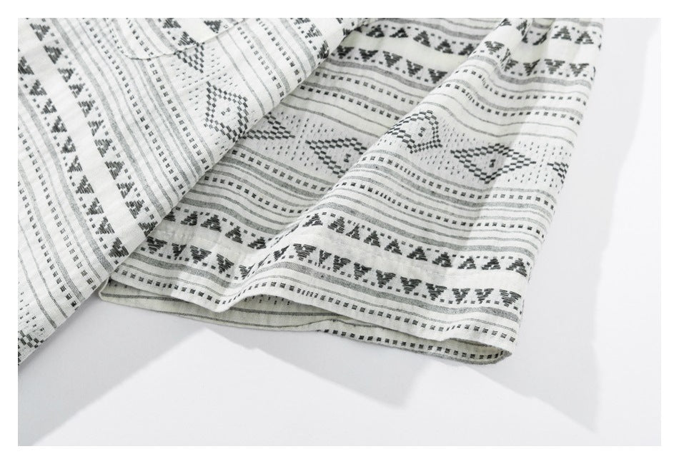 Close-up of the patterned shirt's folded hem and edge stitching on a white background.