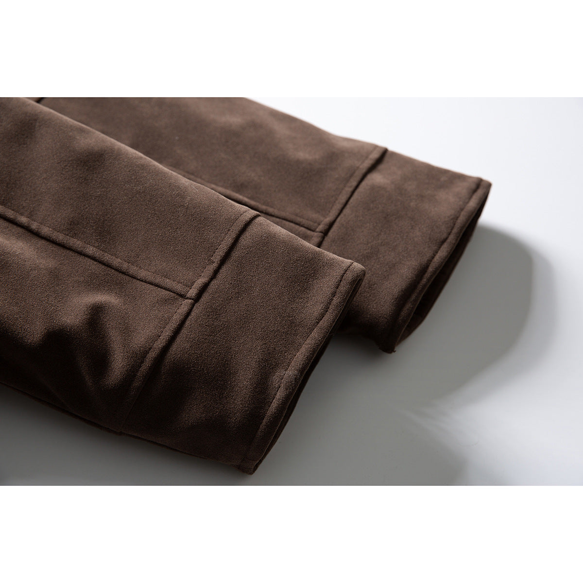 Close-up of the dark brown jacket's stitched sleeve cuffs and hem laid flat.