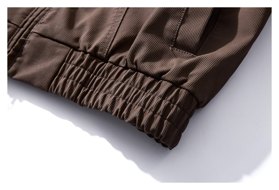 Close-up of the brown jacket's gathered elastic hem and adjacent pocket opening.