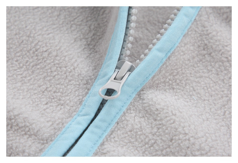 Close-up of a light gray jacket zipper with pale blue binding and a large light-colored pull.