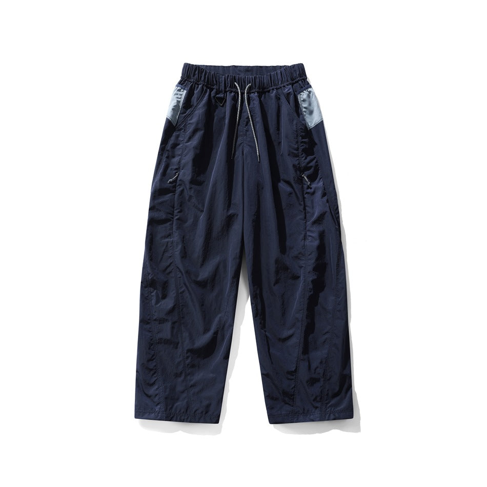 Navy blue wide-leg drawstring pants with light blue-gray side panels and zip pockets, flat lay front view