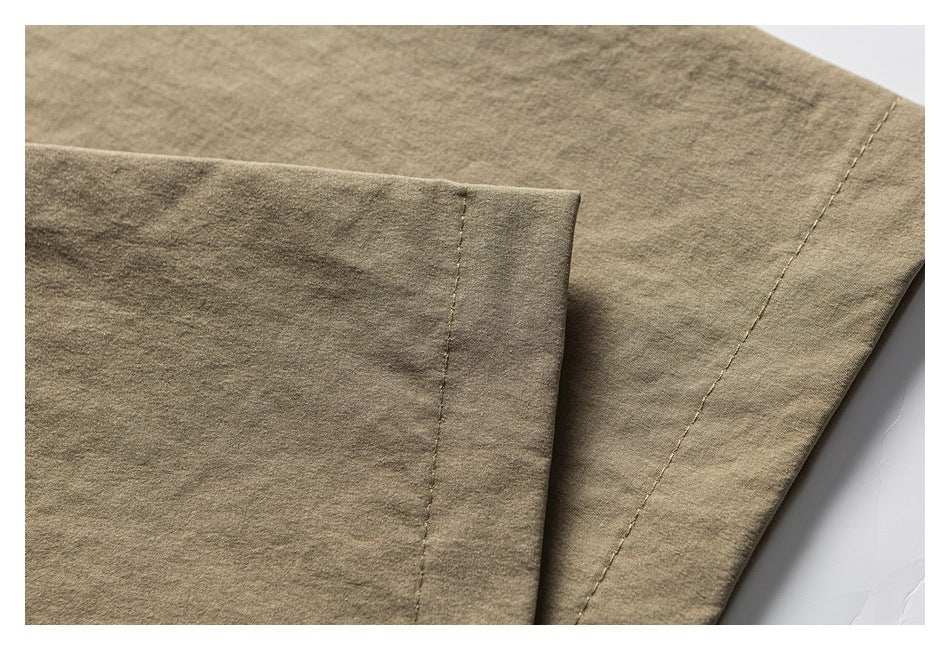 Close-up of khaki shirt fabric showing a folded edge and stitched seam.