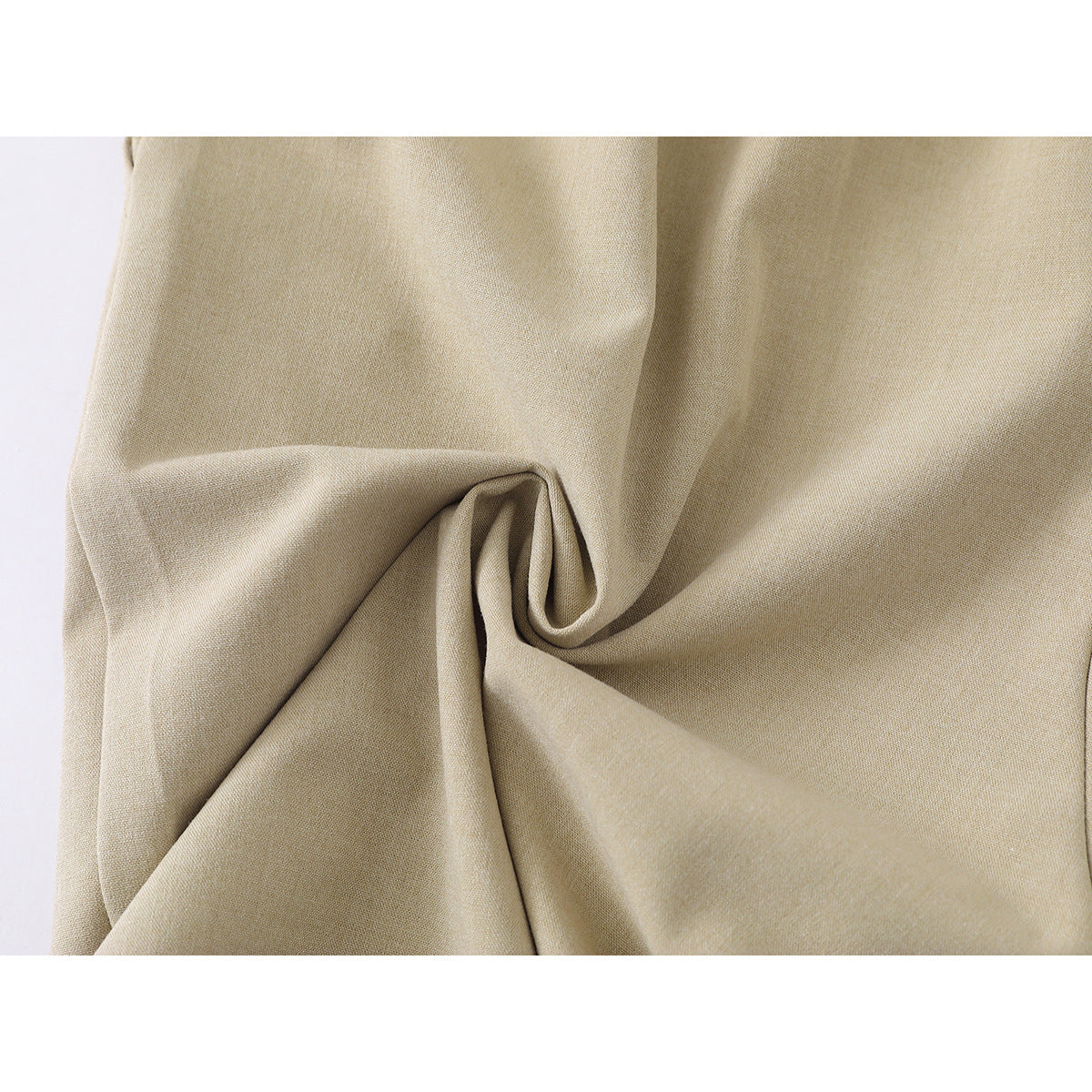 Close-up of beige shorts fabric gathered into a twist to show its drape.
