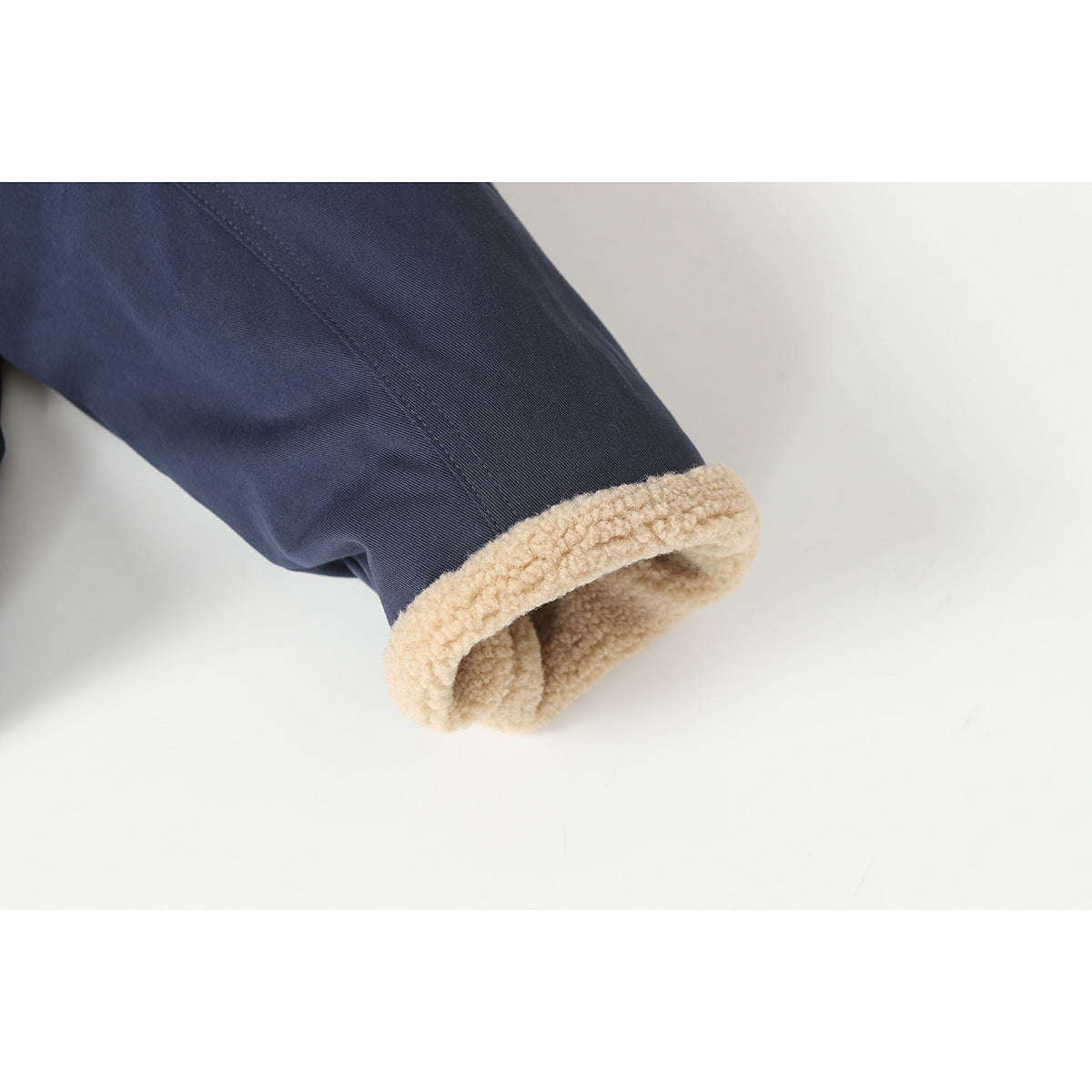 Close-up of a navy jacket sleeve with a thick cream sherpa-lined cuff.