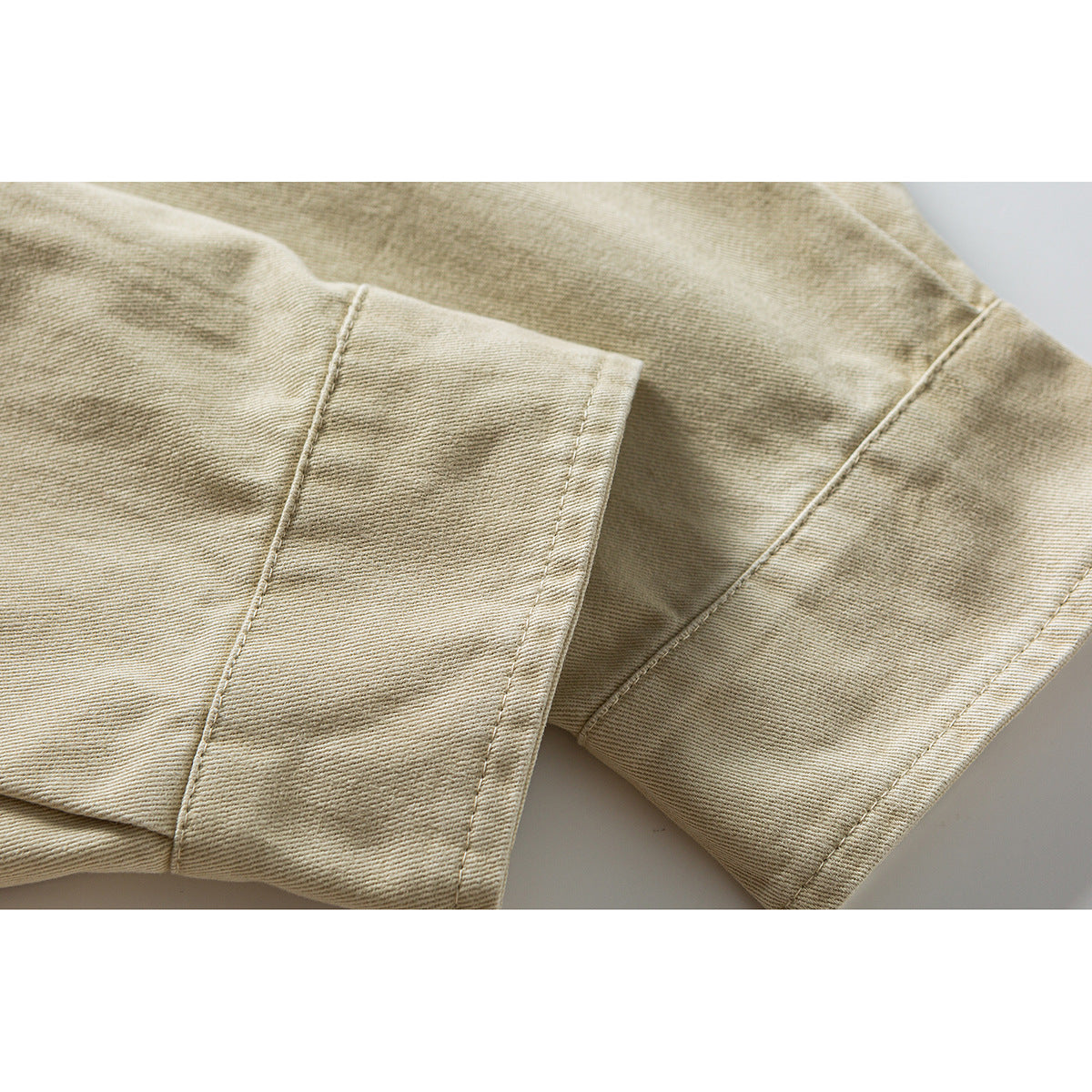 Close-up of the beige shirt’s long sleeve and stitched cuff.