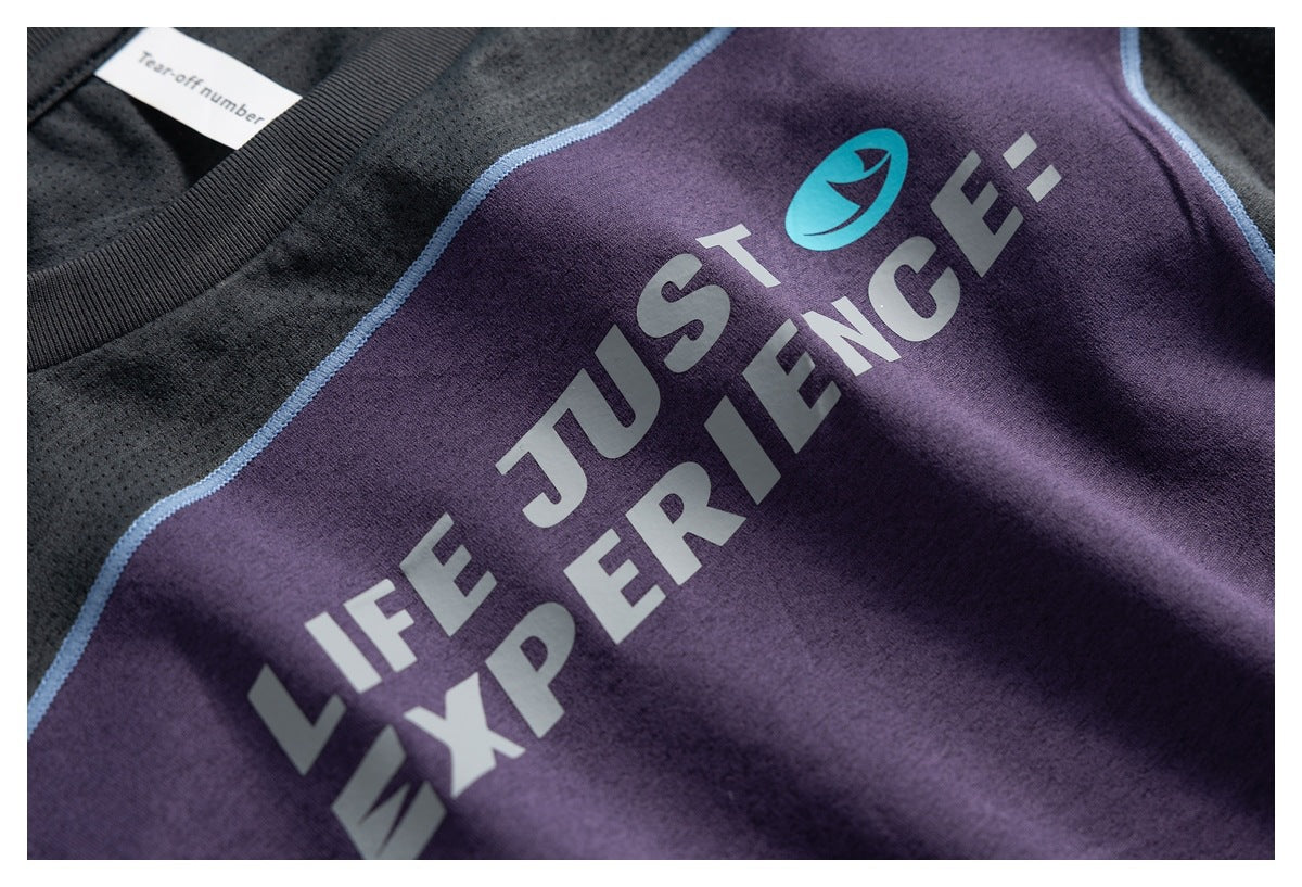 Close-up of the purple front panel showing a large gray English graphic and turquoise emblem, bordered by black fabric and