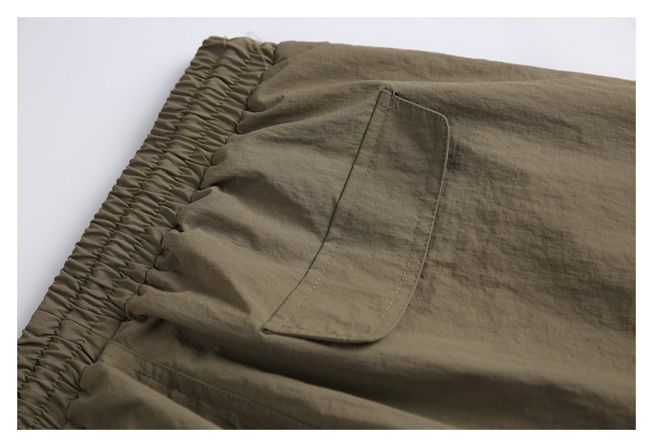 Close-up of an olive-brown pants pocket and gathered elastic waistband.