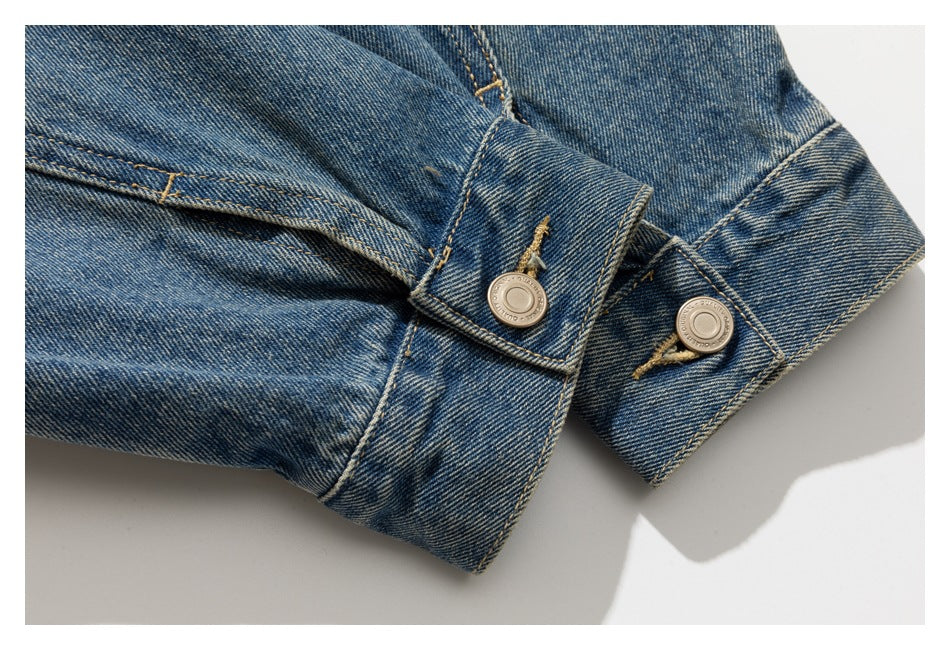 Close-up of two blue denim jacket cuffs with metal buttons and tan stitching.