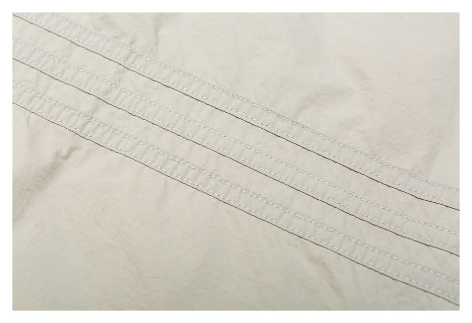 Close-up showing parallel rows of stitching on light beige jacket fabric.